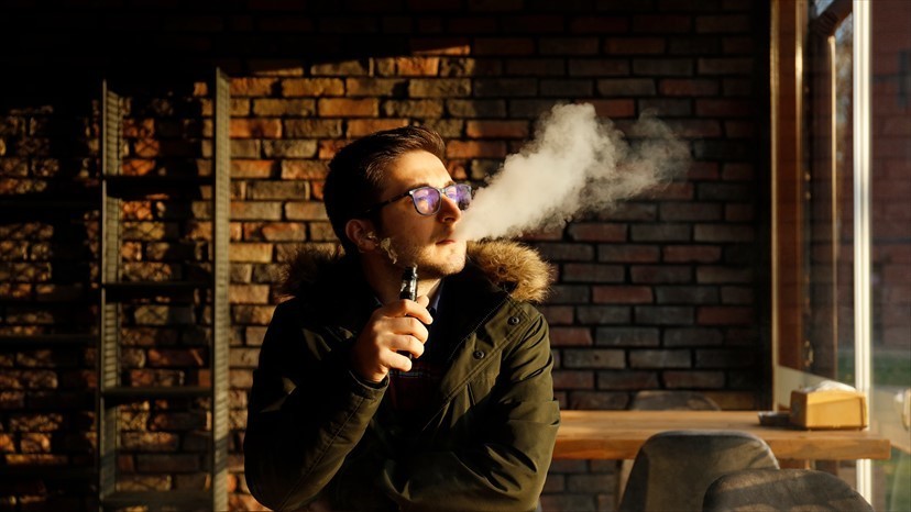 Young man vaping with an e-cigarette